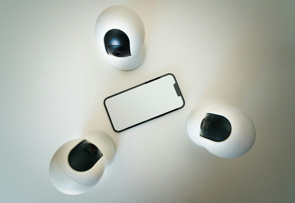 Smartphone surrounded by security cameras on a modern, minimalist setup.