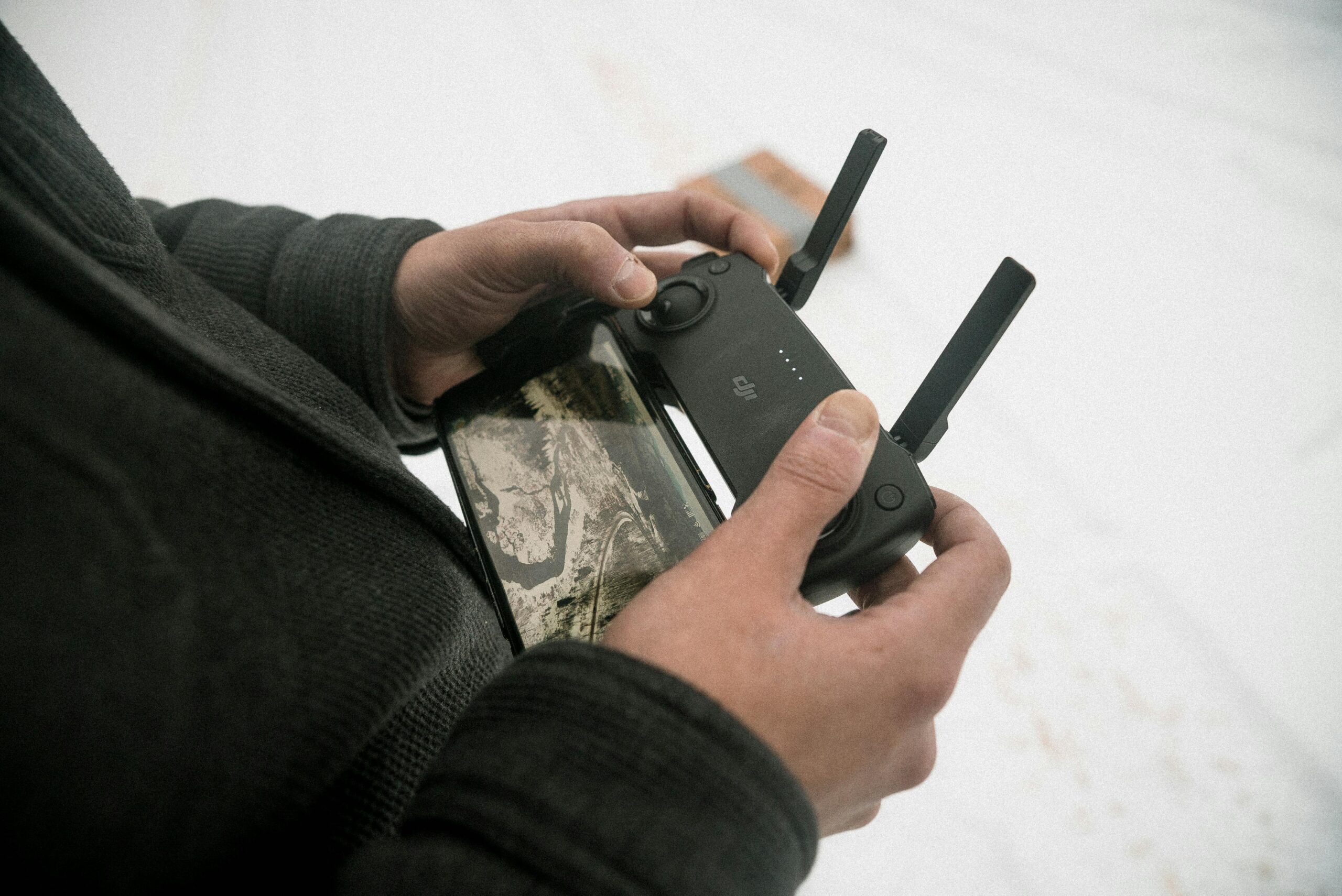 Mobile Privacy in 2025: Navigating the Evolving Threat Landscape Close-up of hands using a drone controller with a smartphone attached outdoors.