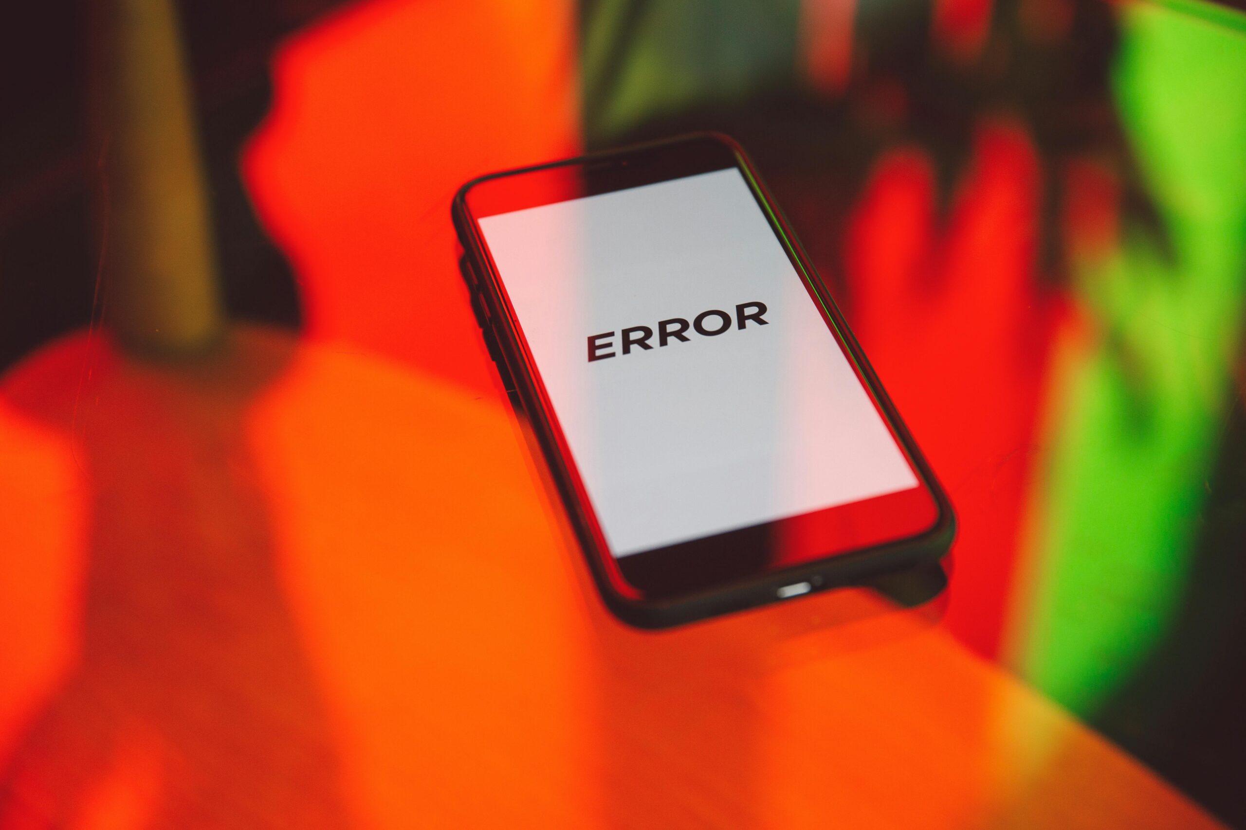 Mobile Privacy in 2025: Navigating the Evolving Threat Landscape A smartphone displaying an 'ERROR' message surrounded by vibrant red and green reflections indoors.