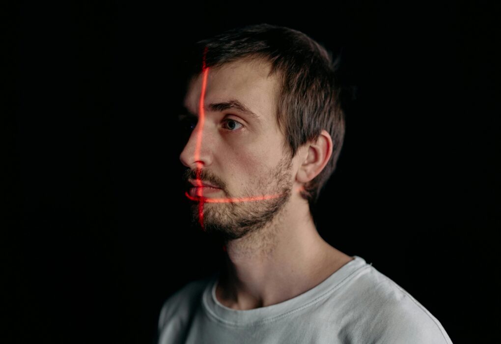 A man undergoes a facial recognition scan with a laser grid in a studio setting.