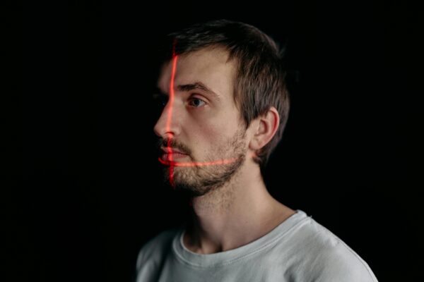 AI Surveillance in 2025: How Smart Devices Are Redefining Privacy and Security A man undergoes a facial recognition scan with a laser grid in a studio setting.