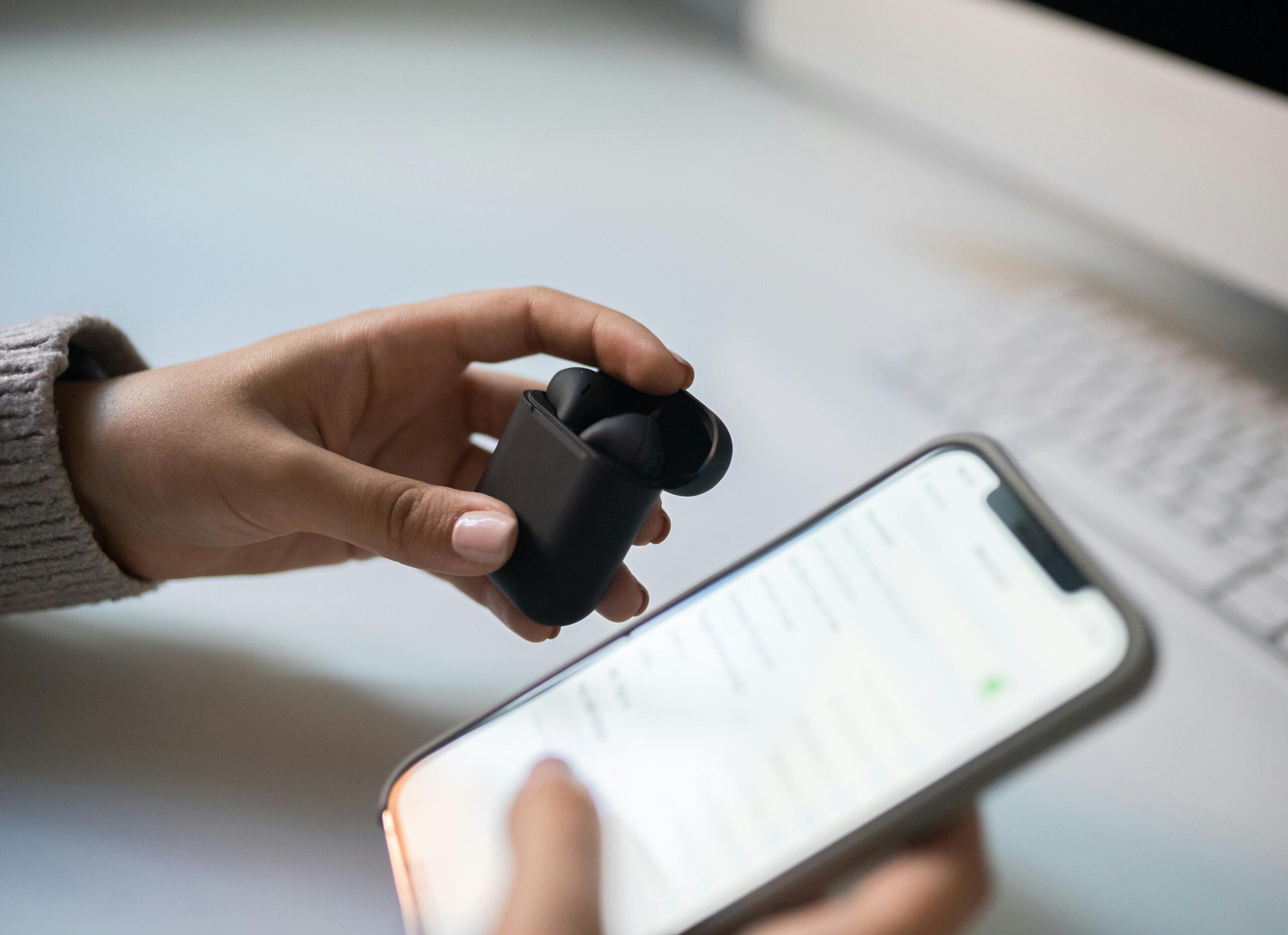The Silent Pairing Threat: How “Ghost Bluetooth” Devices Are Hijacking Phones Close-up view of hands connecting wireless earbuds to a smartphone, emphasizing modern technology.